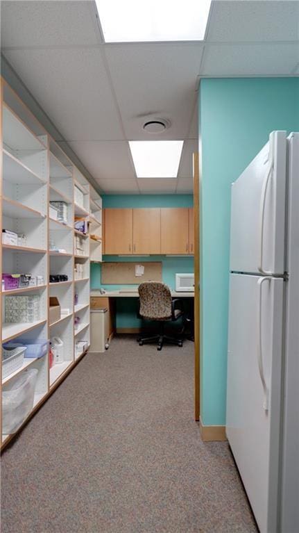 office featuring built in study area, a paneled ceiling, and light carpet