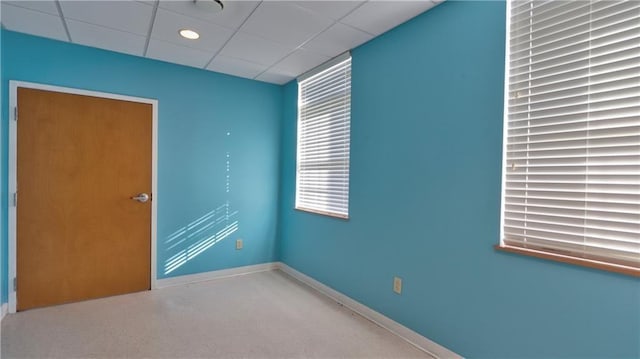 spare room featuring baseboards and a drop ceiling