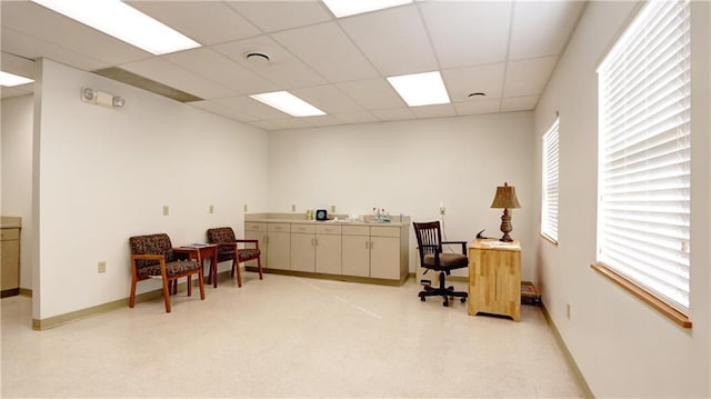 office space featuring baseboards, light floors, and a drop ceiling