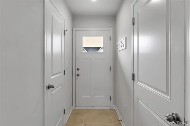 doorway with baseboards and light tile patterned floors