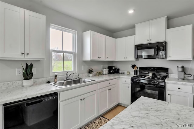 kitchen with light countertops, white cabinets, a sink, and black appliances