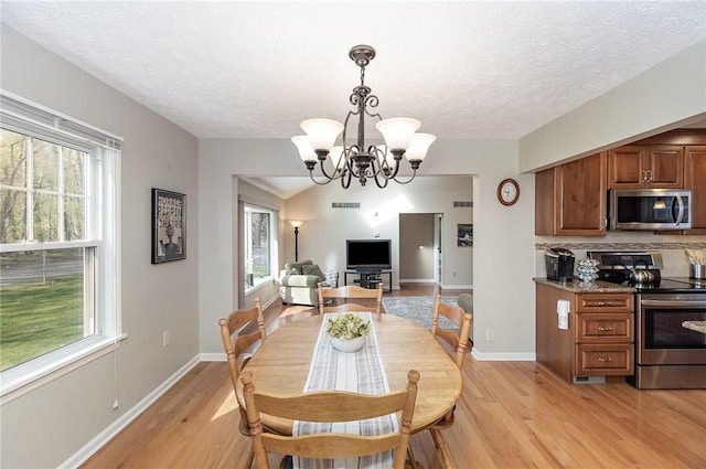 dining area featuring a textured ceiling, an inviting chandelier, baseboards, and light wood-style floors