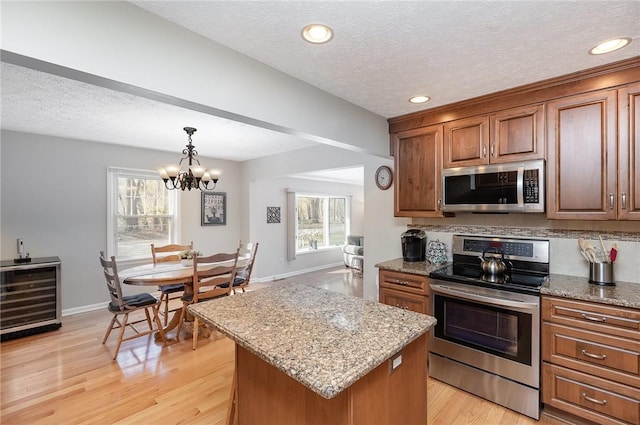 kitchen featuring light stone countertops, appliances with stainless steel finishes, an inviting chandelier, and a center island