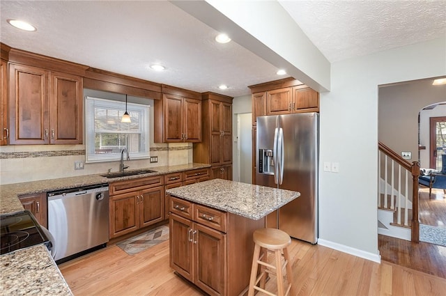kitchen featuring a sink, stainless steel appliances, light wood-style flooring, and a healthy amount of sunlight