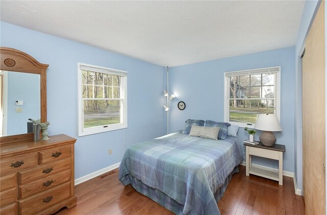 bedroom featuring baseboards, wood finished floors, and visible vents