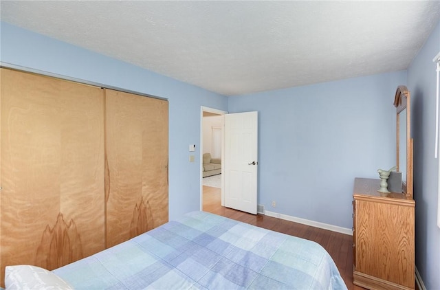 bedroom with baseboards, wood finished floors, and a closet