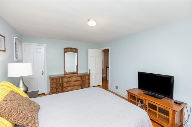 bedroom featuring visible vents, baseboards, and wood finished floors