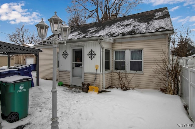 view of front of house featuring board and batten siding, roof with shingles, fence, and a chimney