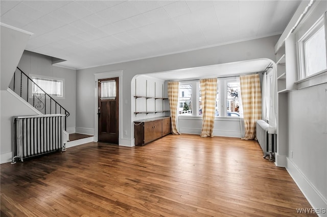 92 Carlyle Ave, Buffalo, NY 14220 - unfurnished living room with radiator, wood finished floors, stairs, and crown molding