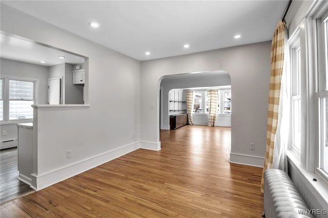 interior space featuring arched walkways, a baseboard radiator, radiator heating unit, recessed lighting, and light wood-style flooring
