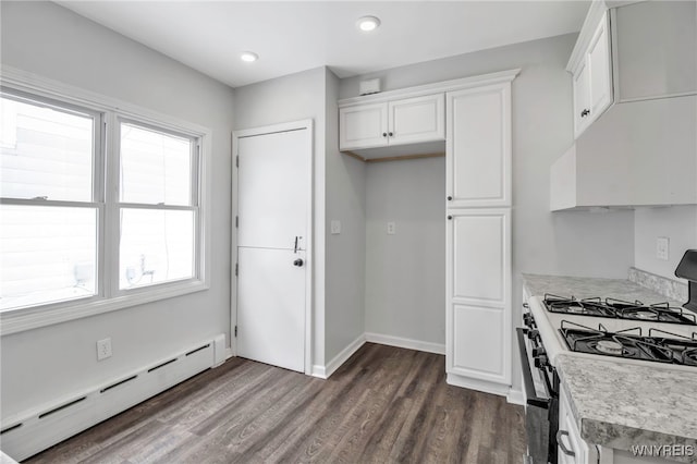 kitchen featuring dark wood-style flooring, gas range oven, light countertops, a baseboard heating unit, and white cabinets