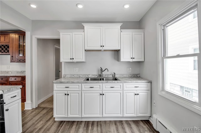 kitchen with light wood-style floors, a sink, a baseboard radiator, and light countertops