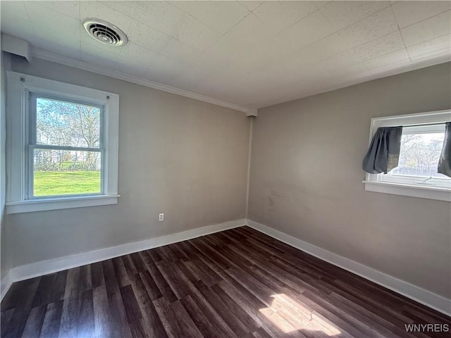 unfurnished room featuring plenty of natural light, ornamental molding, dark wood finished floors, and visible vents