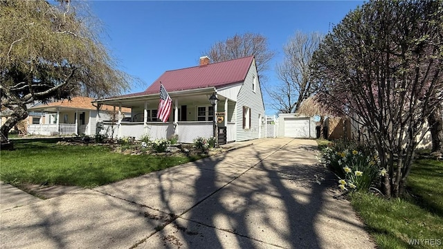 view of front of house featuring concrete driveway, covered porch, a chimney, metal roof, and an outbuilding