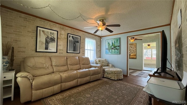 living area with a textured ceiling, ceiling fan, ornamental molding, and brick wall