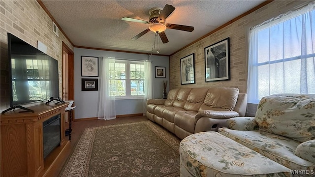 living room featuring crown molding, brick wall, baseboards, a textured ceiling, and a ceiling fan