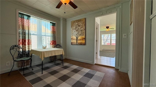dining area featuring baseboards, ceiling fan, baseboard heating, and dark wood-style flooring