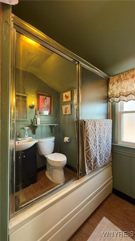 full bathroom with vanity, a shower with door, wood finished floors, toilet, and vaulted ceiling