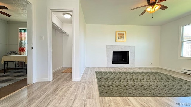 unfurnished living room featuring baseboards, ceiling fan, wood finished floors, and a premium fireplace