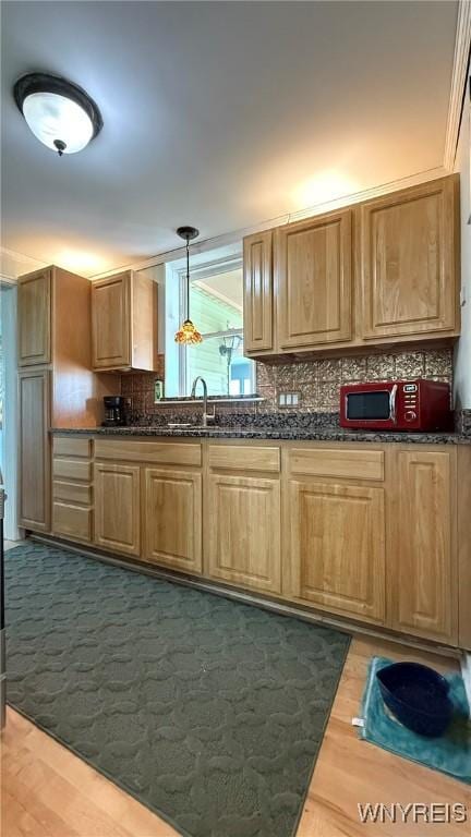 kitchen with hanging light fixtures, dark wood-style floors, a sink, and tasteful backsplash