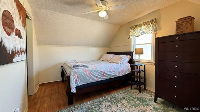 bedroom with baseboards, lofted ceiling, a textured ceiling, and wood finished floors