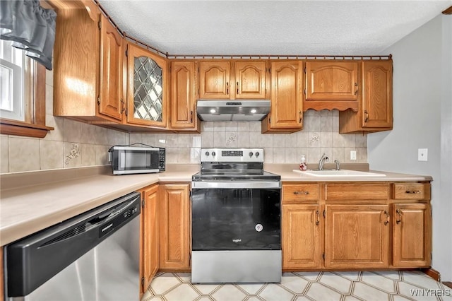 kitchen featuring under cabinet range hood, stainless steel appliances, a sink, and light countertops