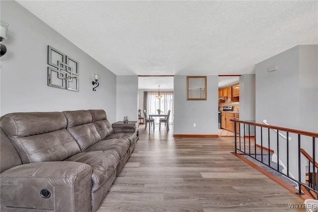 living room with a textured ceiling, baseboards, and light wood-type flooring