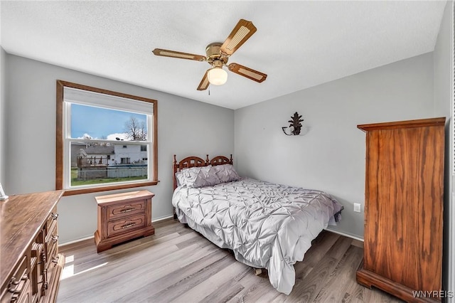 bedroom with baseboards, light wood-style flooring, and ceiling fan