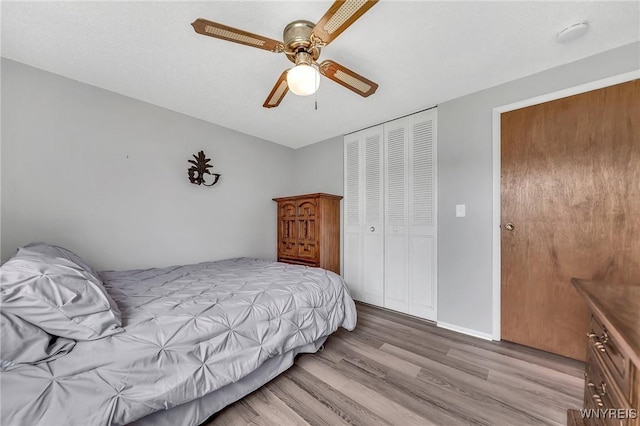 bedroom featuring a ceiling fan, baseboards, light wood finished floors, and a closet