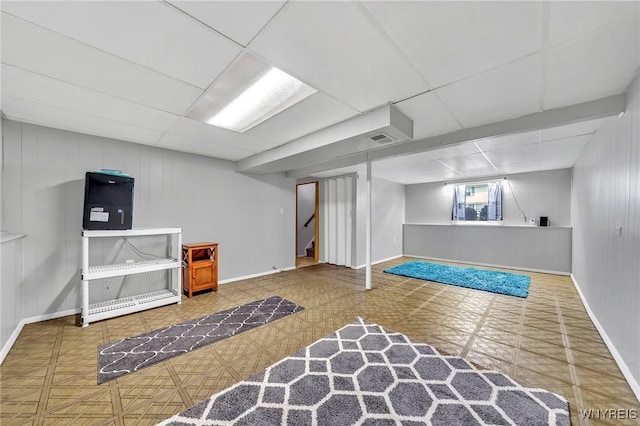 basement featuring visible vents, baseboards, stairs, and a drop ceiling