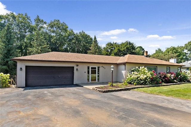 single story home featuring an attached garage, driveway, and a chimney