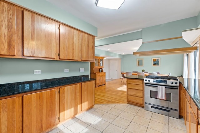 kitchen featuring light tile patterned floors, stainless steel range with gas stovetop, and dark stone countertops