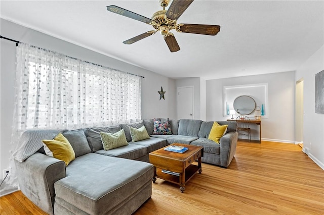 living area featuring baseboards, light wood finished floors, and ceiling fan