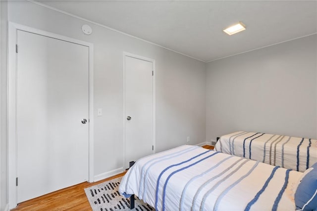 bedroom featuring baseboards, ornamental molding, and light wood-type flooring