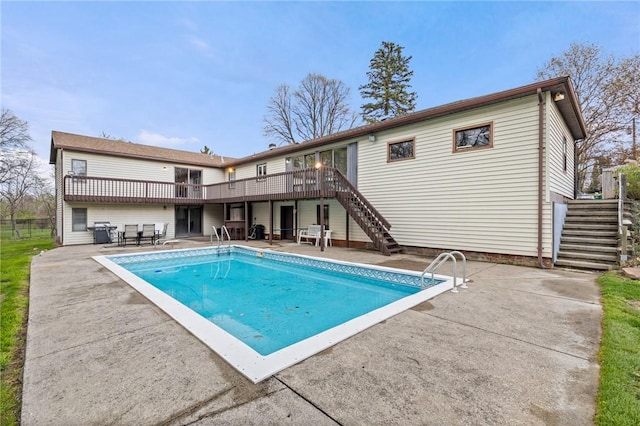 rear view of property featuring an outdoor pool, stairs, a deck, and a patio