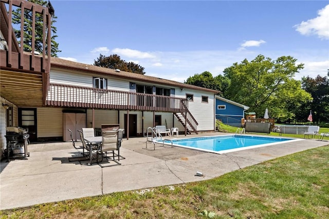 view of pool with a wooden deck, area for grilling, stairway, a fenced in pool, and a patio