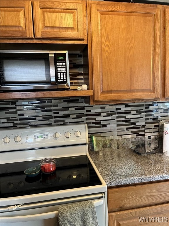 1266 91st St, Niagara Falls, NY 14304 - kitchen with white electric range oven, stainless steel microwave, tasteful backsplash, and brown cabinets