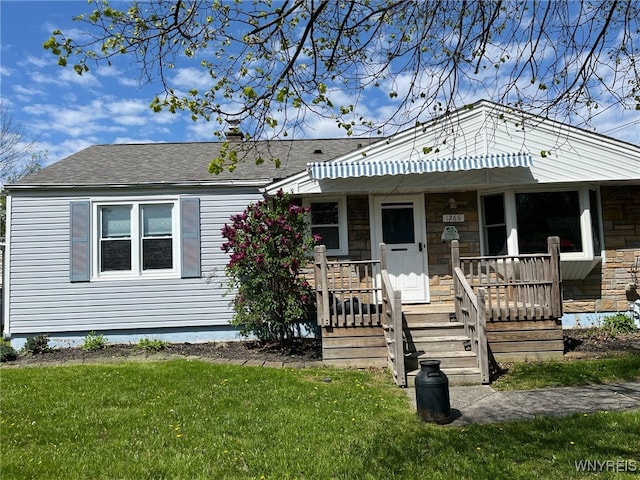 1266 91st St, Niagara Falls, NY 14304 - view of front facade with roof with shingles, a front lawn, stone siding, and covered porch