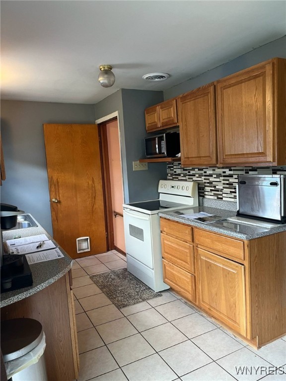 1266 91st St, Niagara Falls, NY 14304 - kitchen featuring electric stove, stainless steel microwave, backsplash, dark countertops, and light tile patterned floors