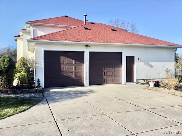 view of home's exterior featuring an attached garage, a shingled roof, stucco siding, and concrete driveway