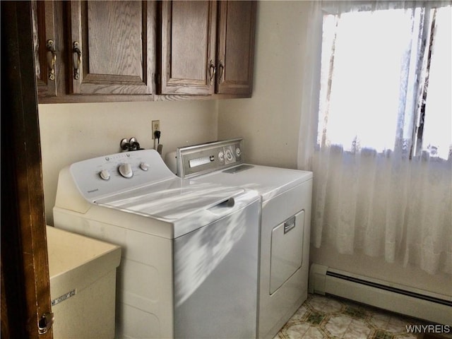 washroom with cabinet space, a sink, washing machine and dryer, and baseboard heating