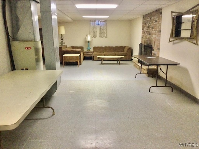 interior space with a brick fireplace, heating unit, and a drop ceiling