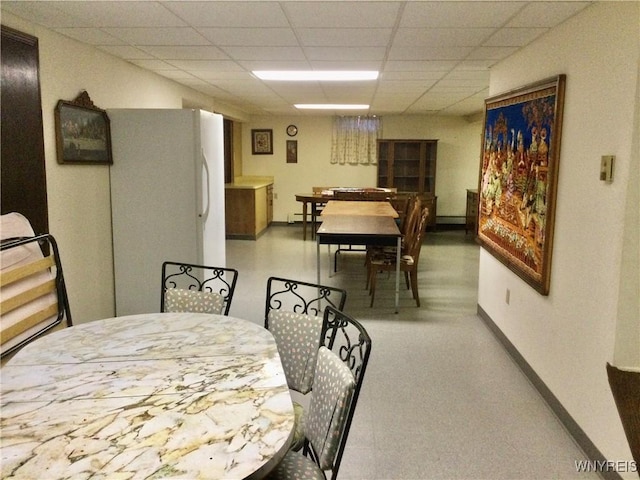 dining area featuring baseboards, a paneled ceiling, and a baseboard heating unit