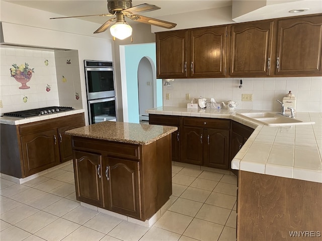 kitchen featuring gas cooktop, backsplash, light tile patterned flooring, and double oven