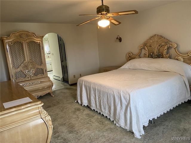 carpeted bedroom featuring ensuite bathroom, arched walkways, ceiling fan, and a baseboard radiator