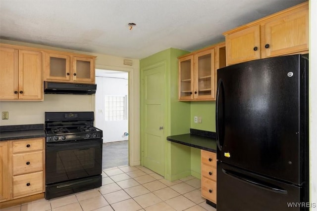 kitchen featuring dark countertops, built in desk, black appliances, glass insert cabinets, and under cabinet range hood