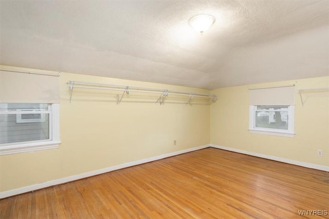 walk in closet with light wood-style floors and lofted ceiling