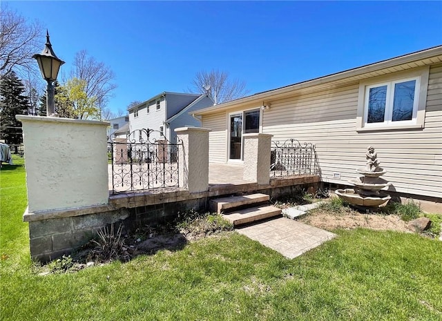 rear view of house featuring a lawn and fence