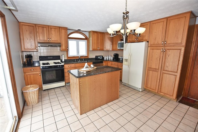 kitchen with appliances with stainless steel finishes, a center island, a sink, a notable chandelier, and under cabinet range hood