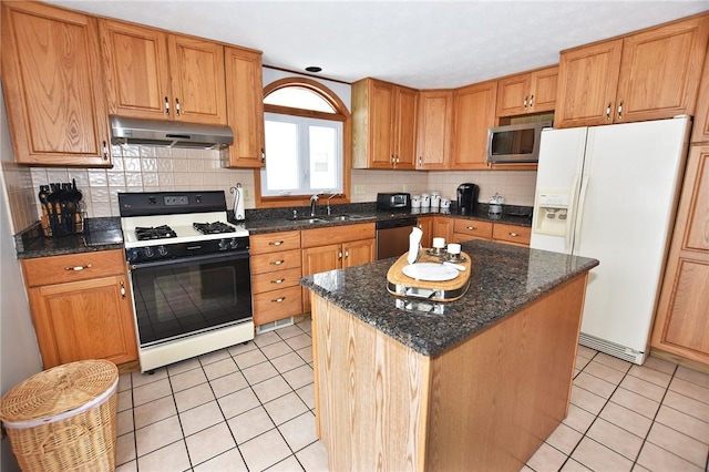 kitchen with a sink, light tile patterned floors, under cabinet range hood, and stainless steel appliances